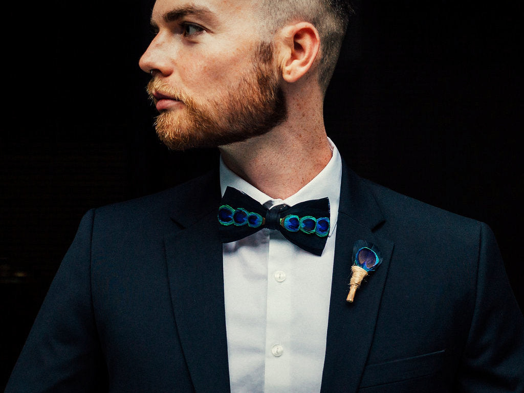 Groom wearing a handmade feather bow tie and lapel pin